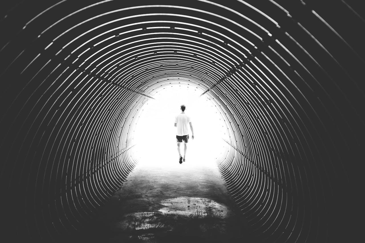 Grayscale Photo of Man Walking in Hole